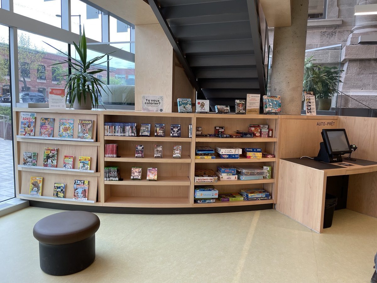 Espace de bibliothèque avec banque de prêt adaptée et étagères accessibles